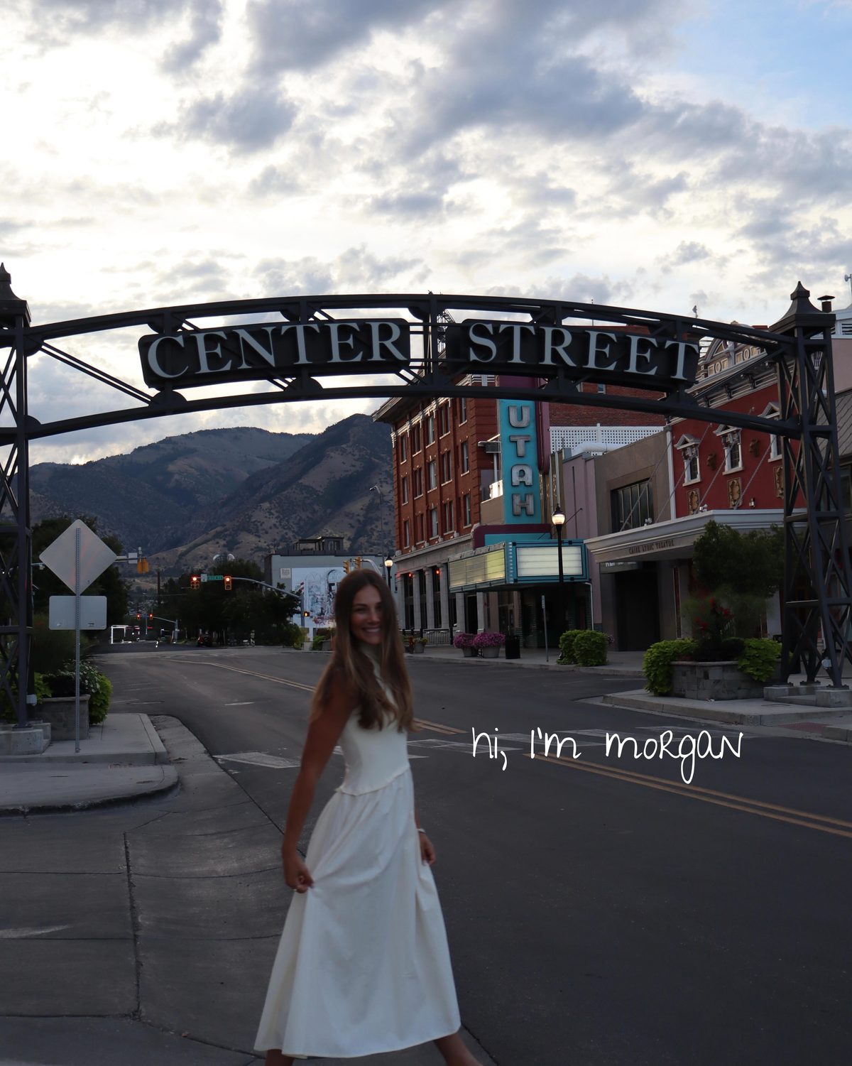 Morgan Hymas in a white dress under the Center Street arch in downtown Logan, Utah