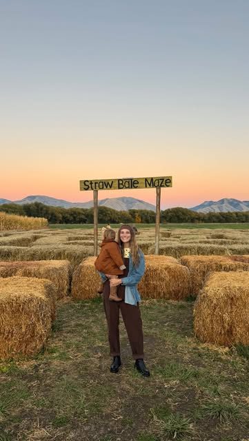 Morgan holding her child at a straw bale maze at sunset